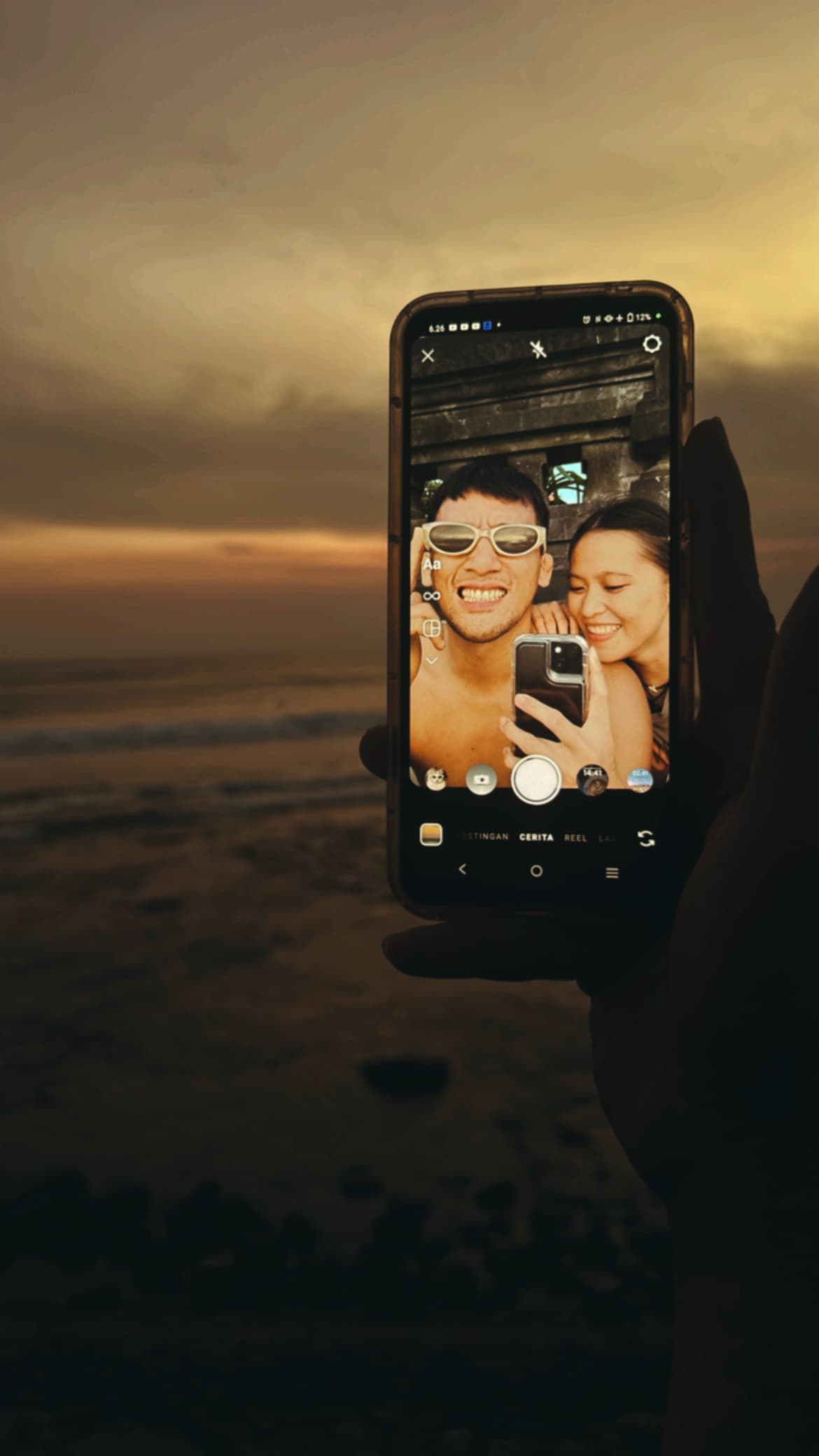 Brenda and Marck reflected in a phone against the sunset