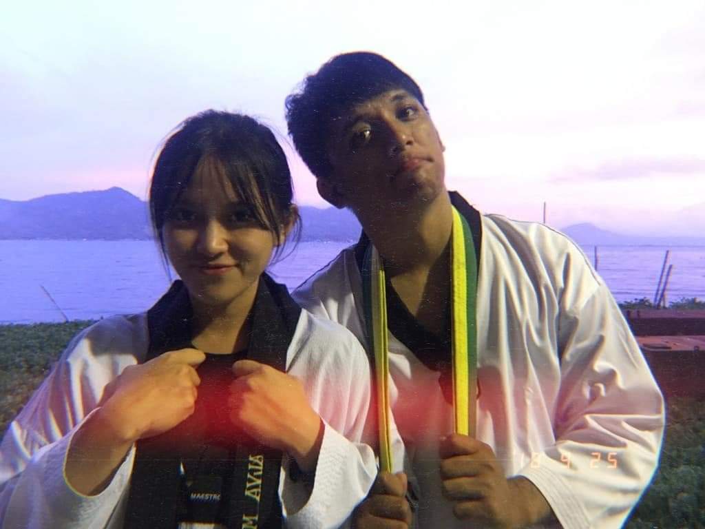 Brenda and Marck in taekwondo uniforms beside the water